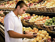 Man examines an apple for purchase. - Copyright – Stock Photo / Register Mark